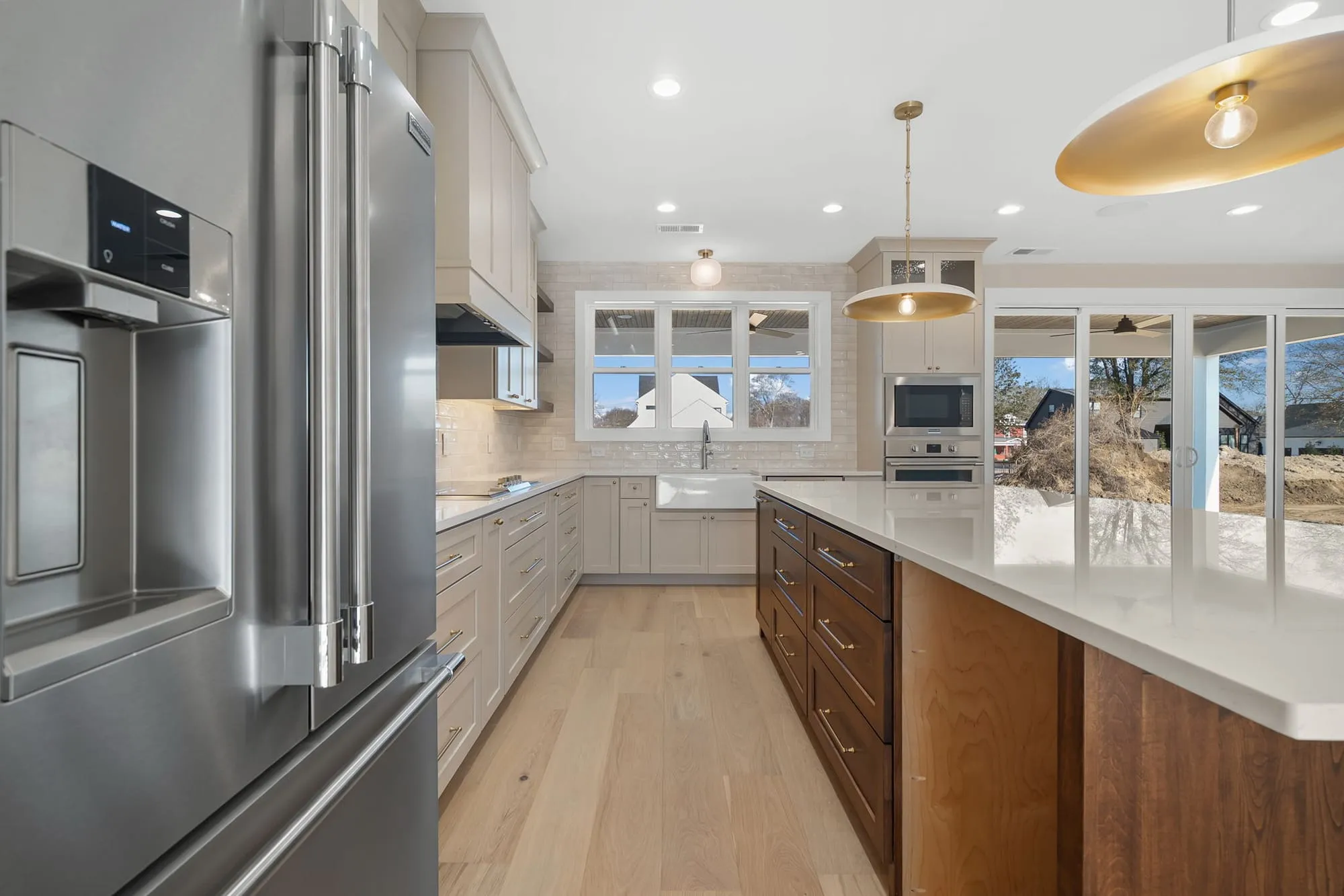 A Trivium custom kitchen with a farmhouse sink and brass pendants