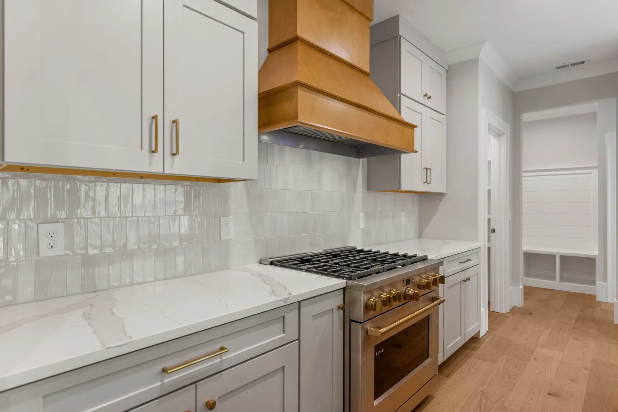 Custom kitchen with a wood range hood, marble counters, and brass hardware