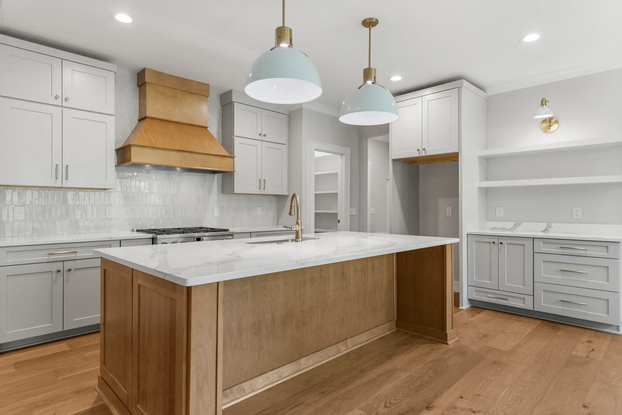 Custom kitchen with a wood range hood, island, and pendant lighting